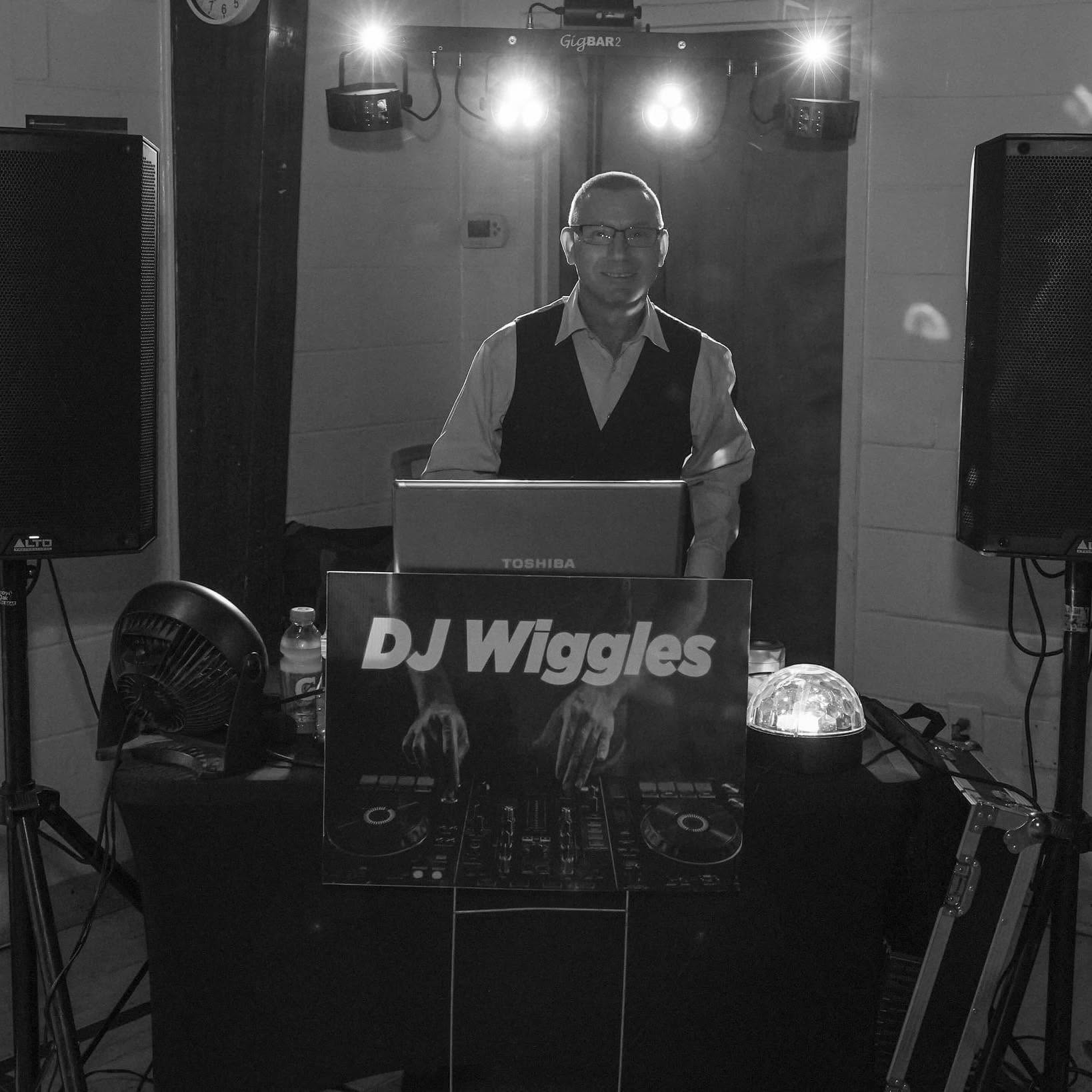 DJ Wiggles standing with his sound and lighting setup, smiling at the camera